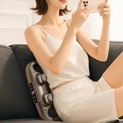 Woman using a massage chair with a phone in her hand, wearing a white top and shorts.